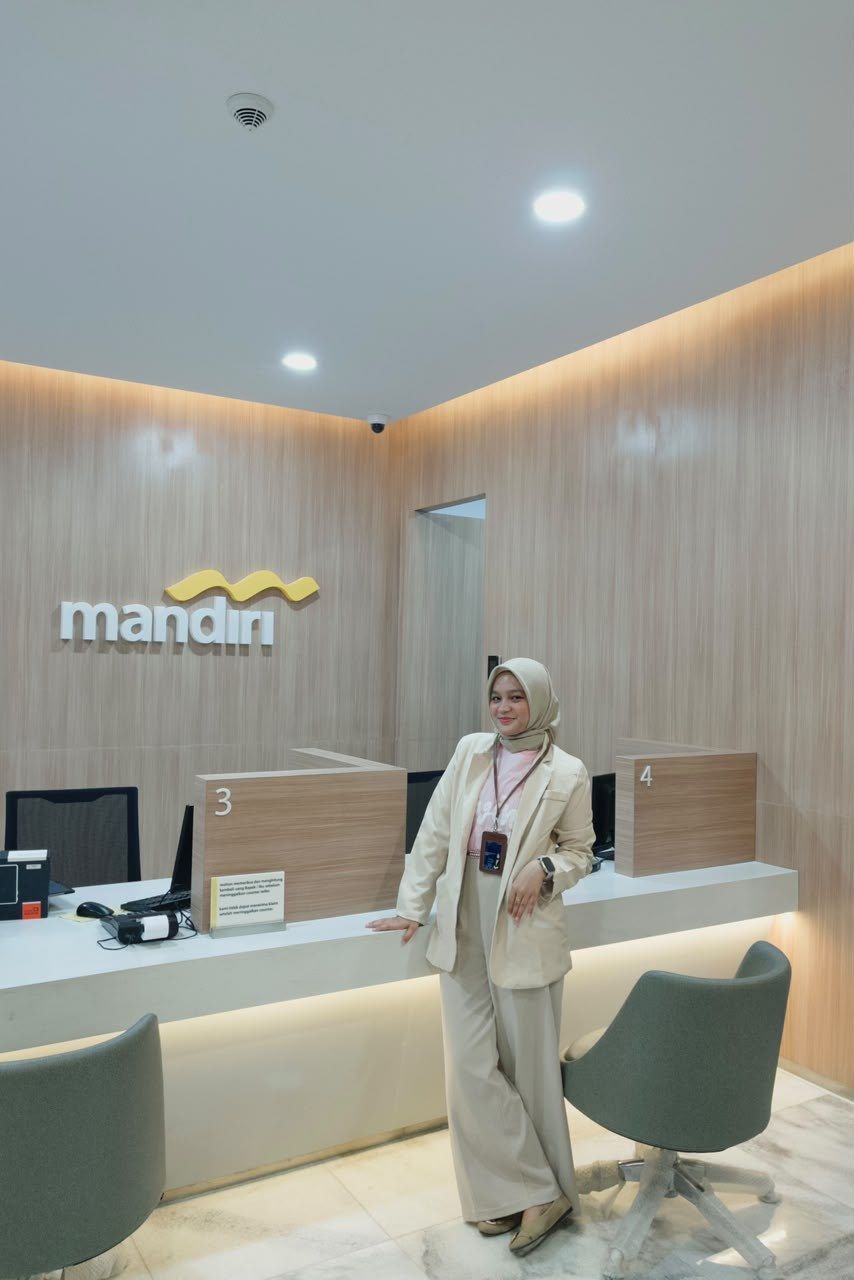 Nasywa Raihanah Fatra berdiri di meja teller kantor cabang Bank Mandiri
